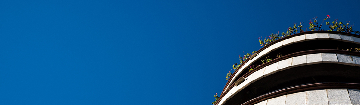 Bottom-up view of apartment building stores with clear blue sky Exterior view of the last three stores of an apartment building against a clear blue sky